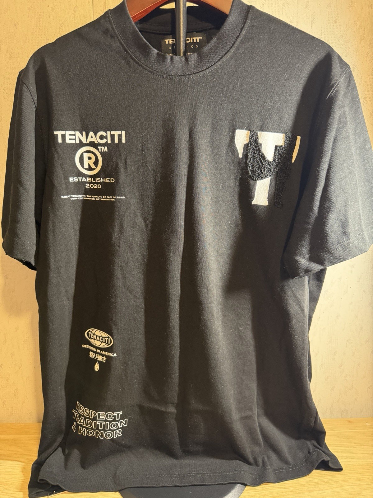Tenaciti Studios t-shirt features a large fuzzy “T” logo on the right chest SZ S