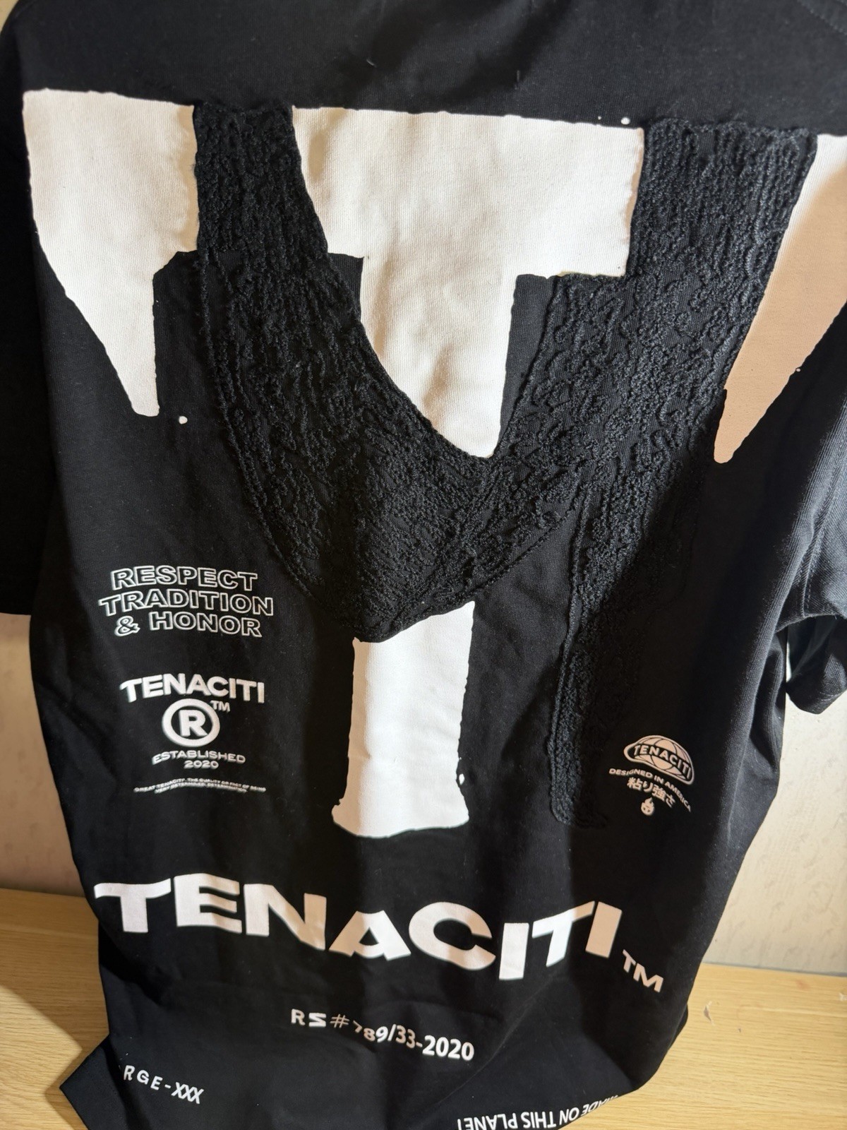 Tenaciti Studios t-shirt features a large fuzzy “T” logo on the right chest SZ S