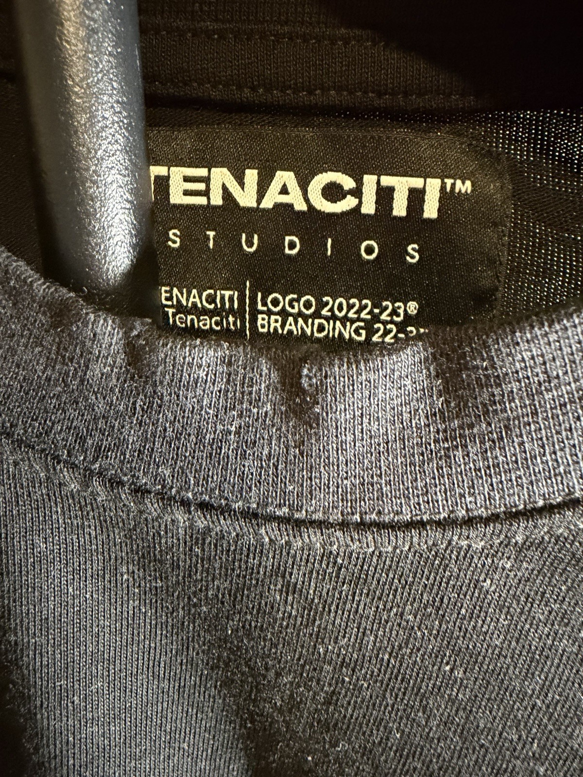 Tenaciti Studios t-shirt features a large fuzzy “T” logo on the right chest SZ S